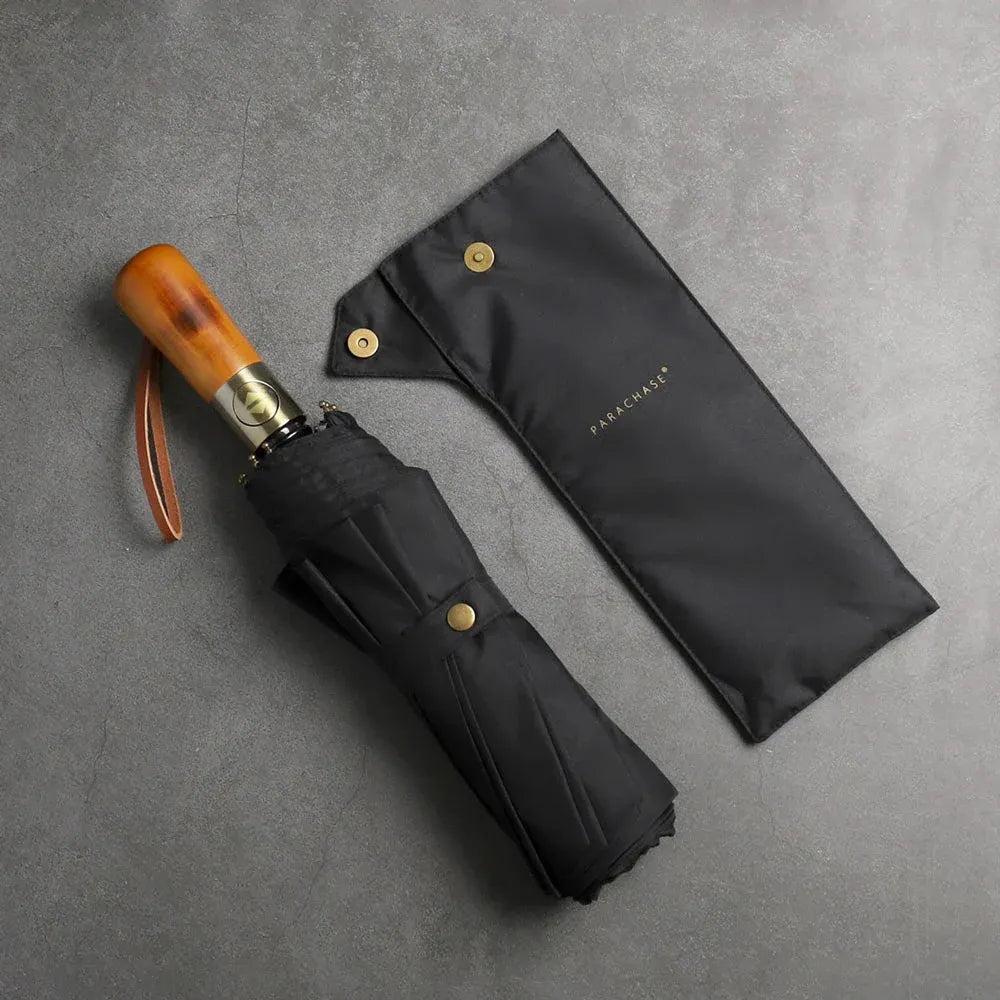 The large automatic folding umbrella with a luxury wood handle in black, shown closed next to its sleeve.