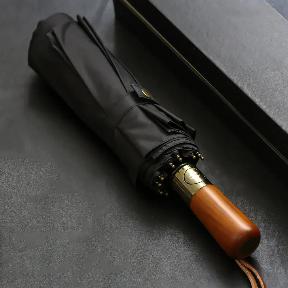 Profile view of the closed black large folding umbrella, highlighting the natural wood handle.