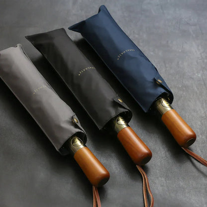 The grey, black, and navy blue large folding umbrellas shown partially inside their sleeves.