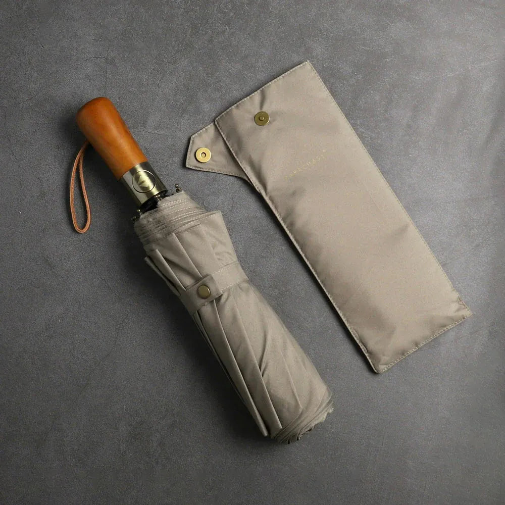 The large automatic folding umbrella with a luxury wood handle in khaki, shown closed next to its sleeve.