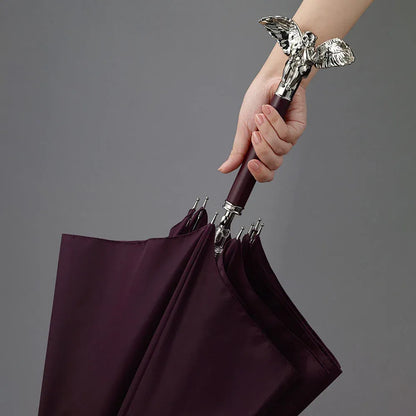 A woman's hand holding the silver angel handle while opening the burgundy umbrella.