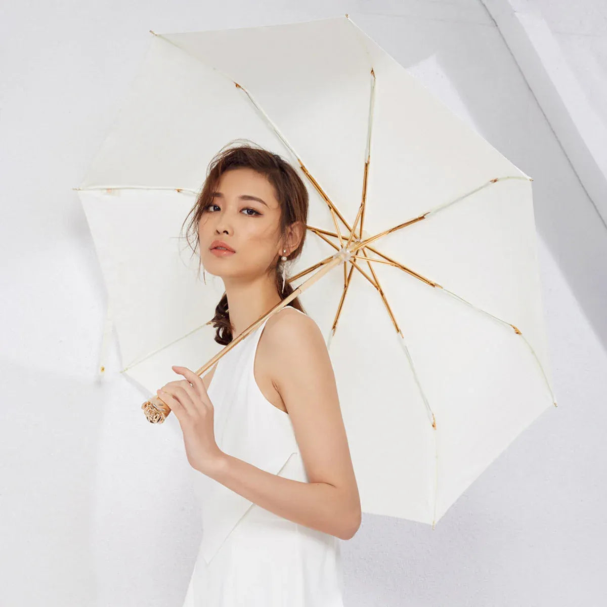 A model holding the open white luxury ladies umbrella with the golden rose handle in front.