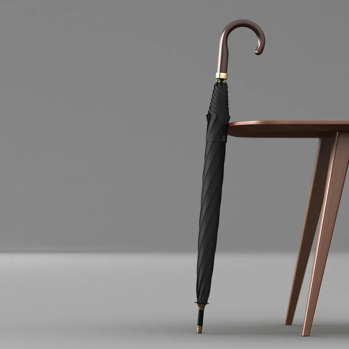 Lifestyle shot of the closed black luxury leather handle umbrella leaning against a table.