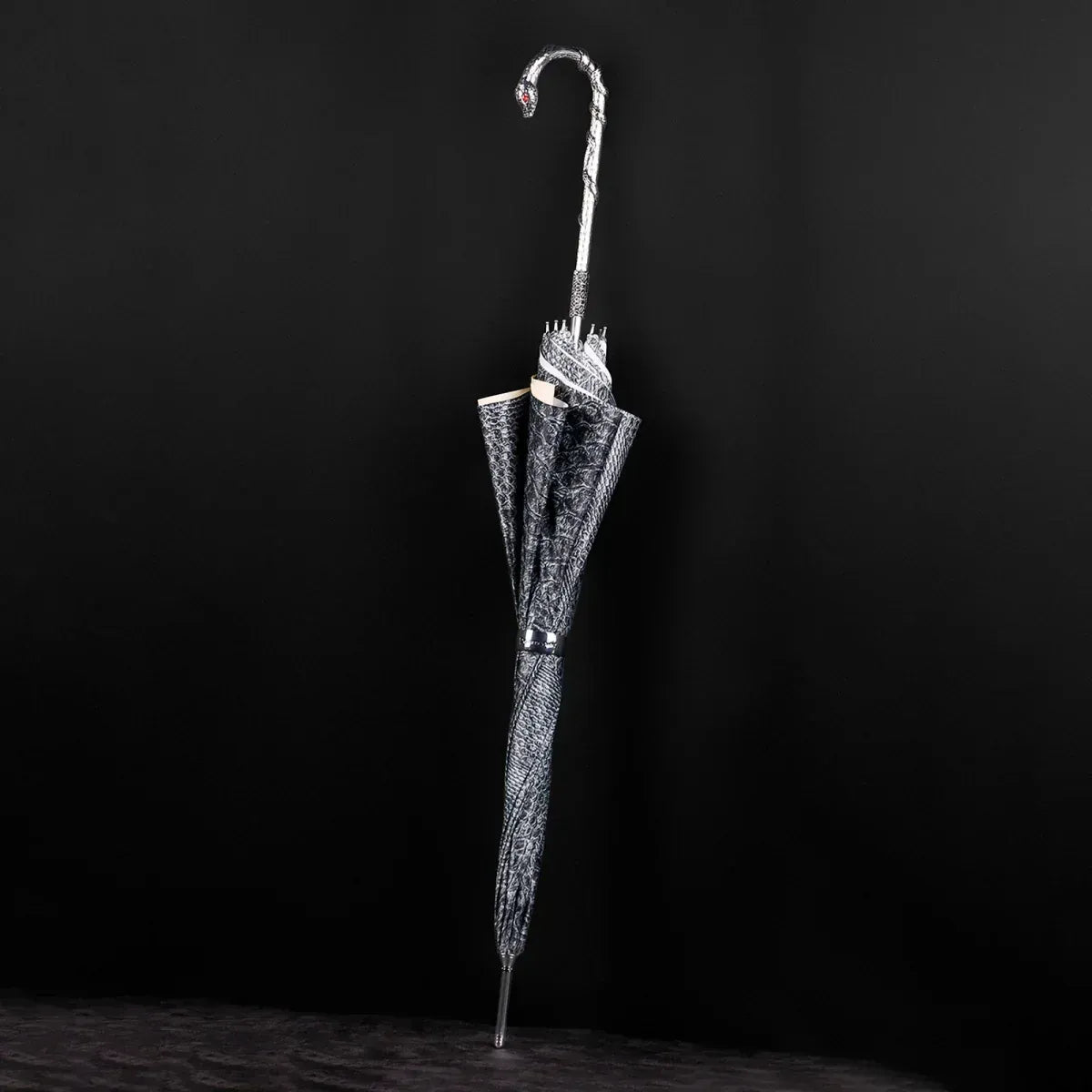 The luxury snake umbrella shown closed, highlighting the serpent pattern canopy and silver snake handle.