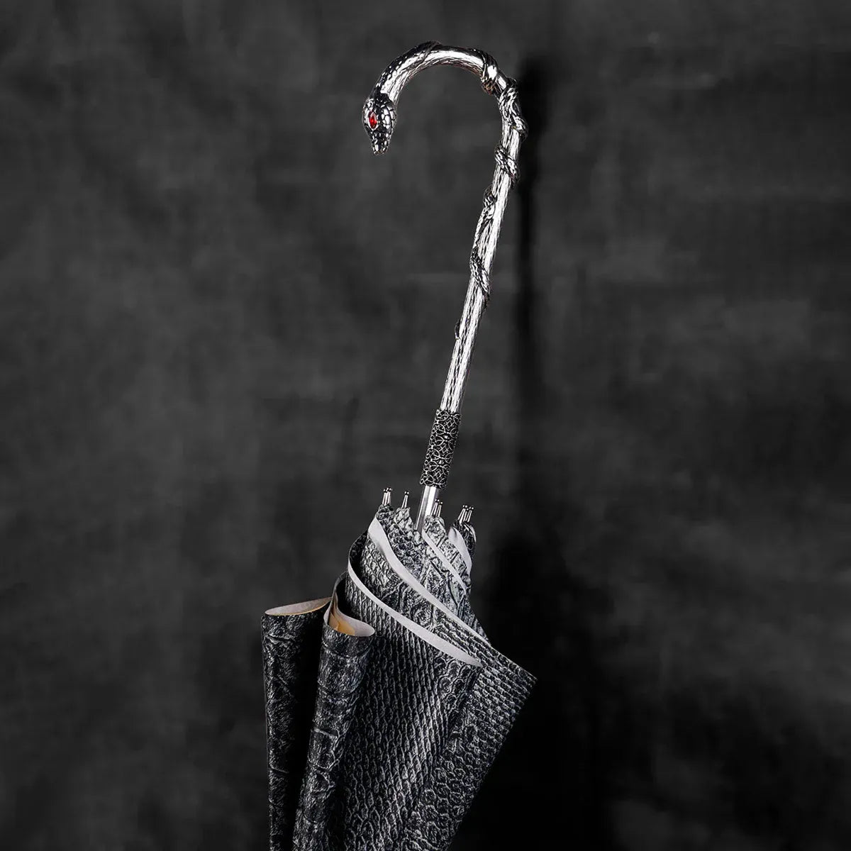 Extreme close-up of the silver snake head handle, showing the intricate scales and red crystal eyes.