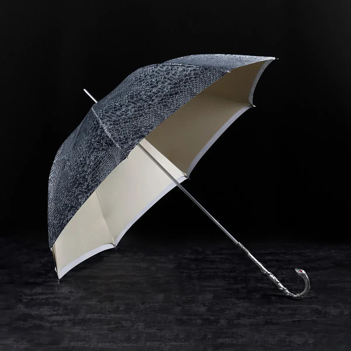 Profile view of the open luxury snake umbrella resting on a dark surface.