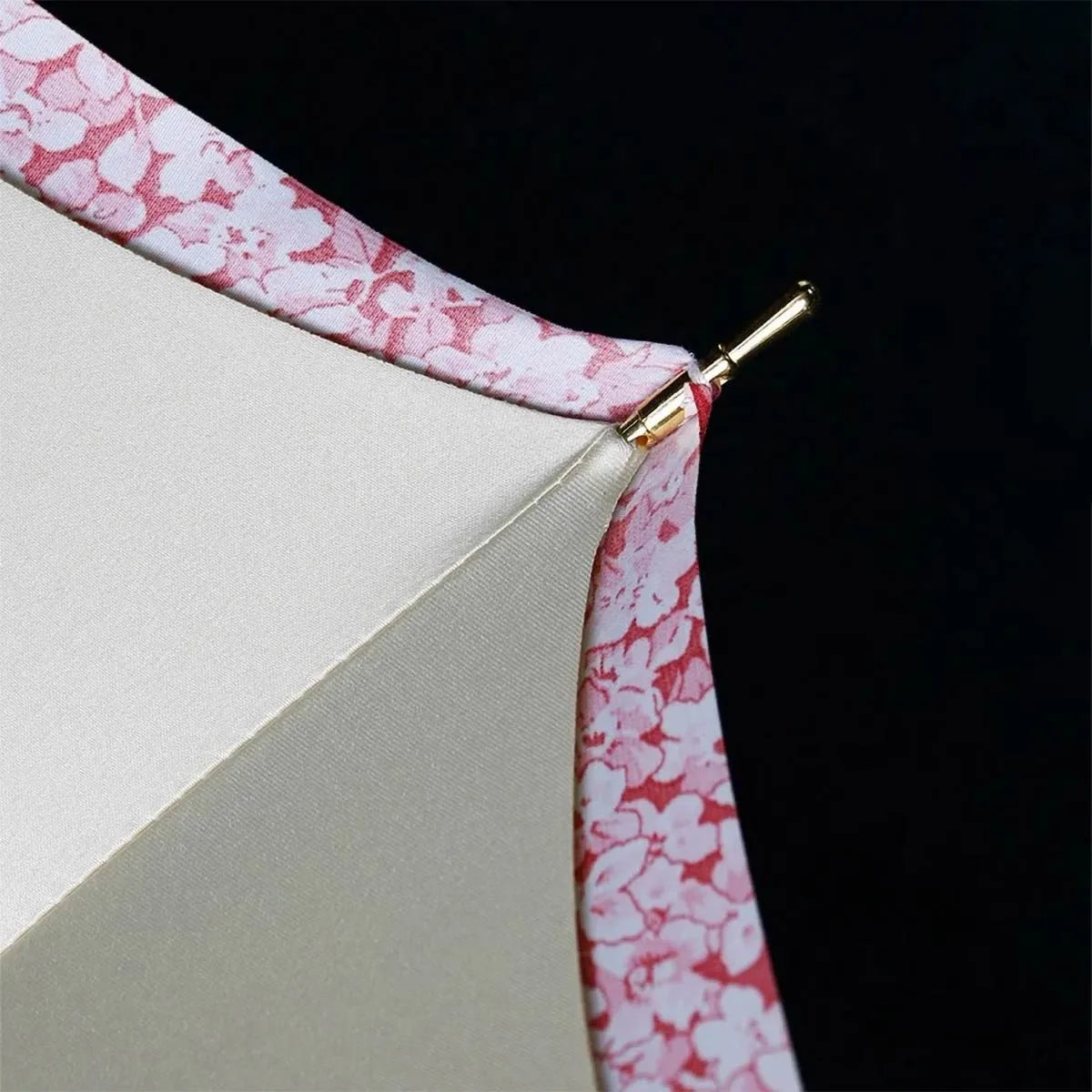 Detail shot of the canopy edge showing the pink floral outer layer, cream inner layer, and golden tip.