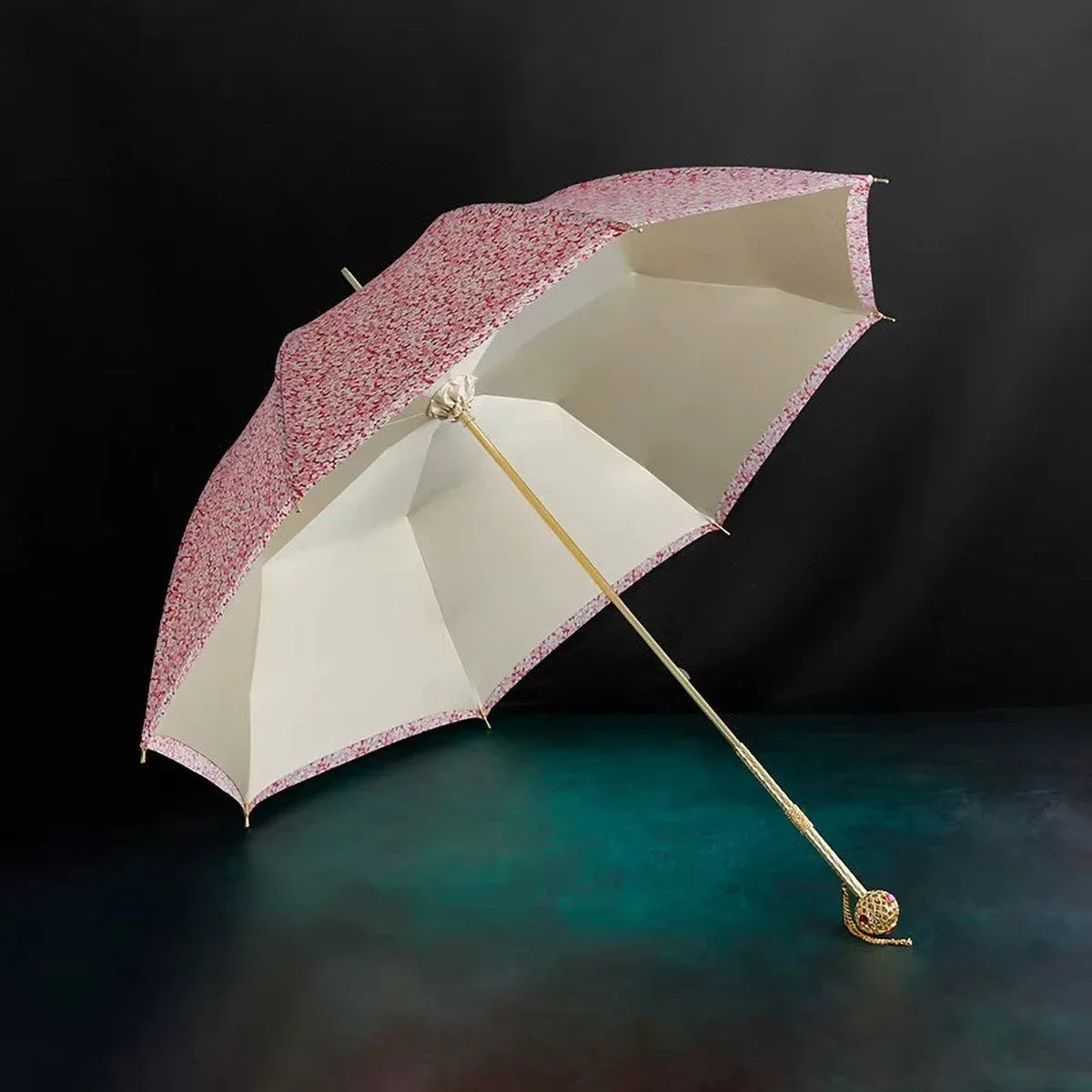 Angled view of the open pink floral umbrella resting on a dark surface, highlighting the double layer canopy.