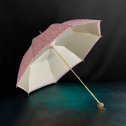 Angled view of the open pink floral umbrella resting on a dark surface, highlighting the double layer canopy.