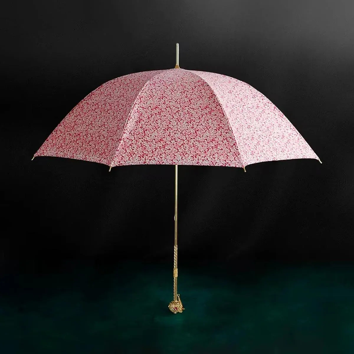 Full profile view of the open pink floral umbrella with its ornate luxury gold handle.
