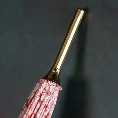 Close-up of the elegant golden top ferrule tip of the closed pink floral umbrella.