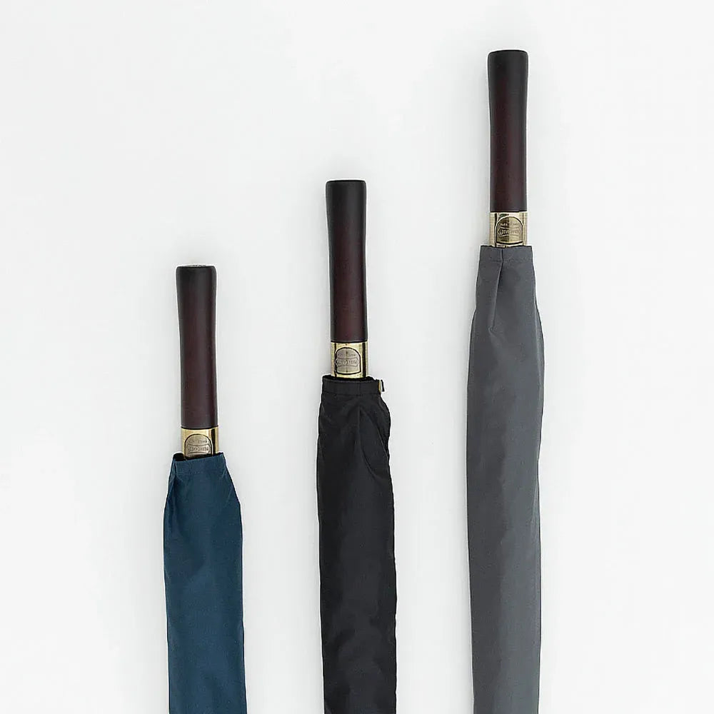 Close-up showing the straight wood handles of the premium big rain umbrellas in navy, black, and grey.