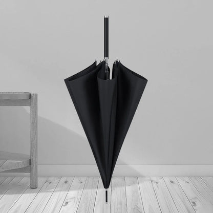 The closed black premium long handle umbrella standing on a wooden floor in a room setting.