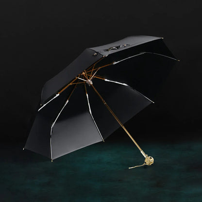 The open black Prestige folding umbrella with its crystal-embellished gold handle, showcasing the black interior lining.
