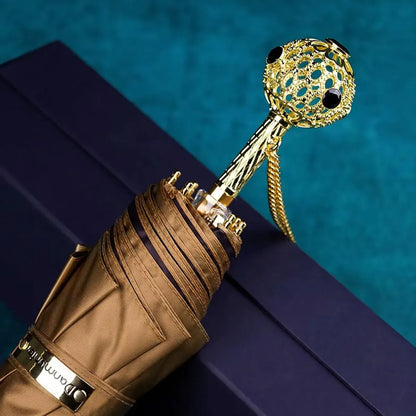 The Prestige crystal handle folding umbrella for women in brown, showing the ornate gold handle with black crystals.