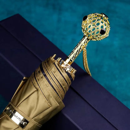 The Prestige crystal handle folding umbrella for women in gold, showing the ornate gold handle with black crystals.