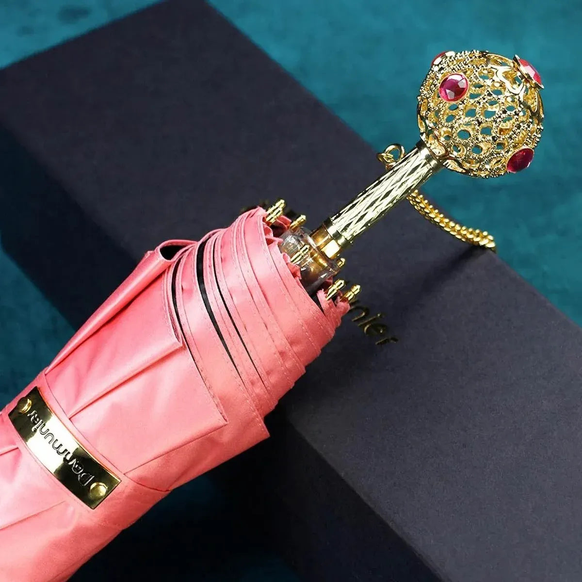 The Prestige crystal handle folding umbrella for women in pink, showing the ornate gold handle with red crystals.