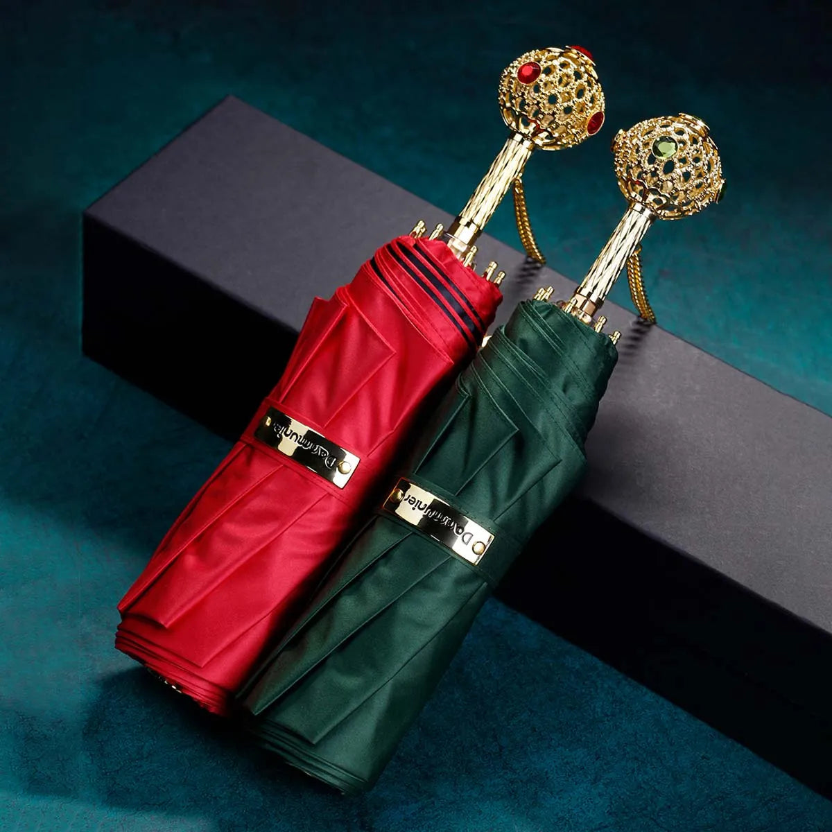 The red and green Prestige crystal handle folding umbrellas displayed together, partially closed.