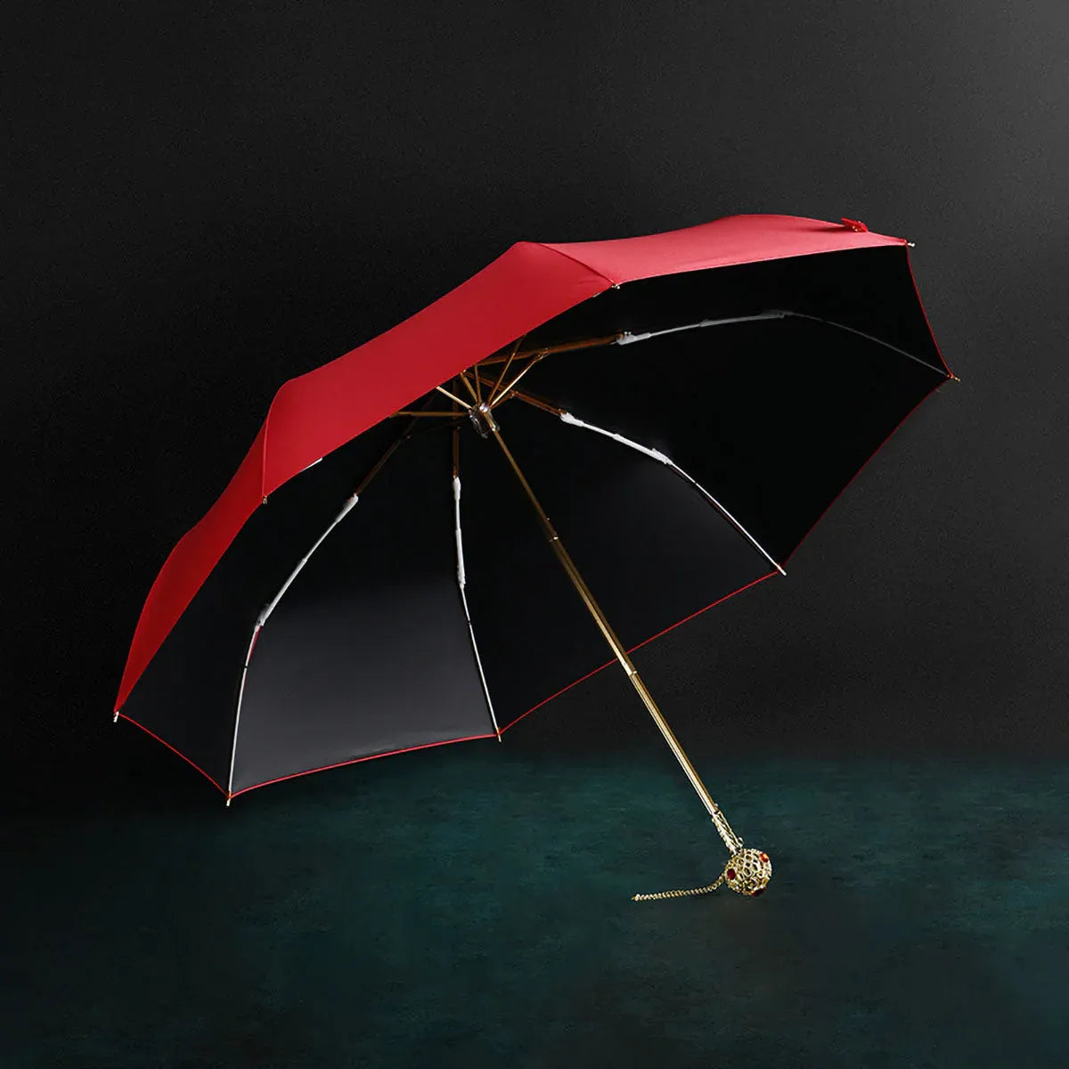 The open red Prestige folding umbrella with its crystal-embellished gold handle, showcasing the black interior lining.