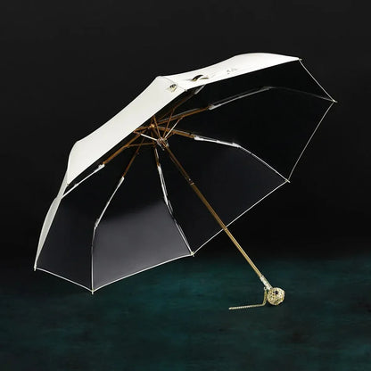 The open white Prestige folding umbrella with its crystal-embellished gold handle, showcasing the black interior lining.
