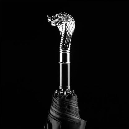 Dramatic close-up of the sculpted silver cobra head handle against a pure black background.