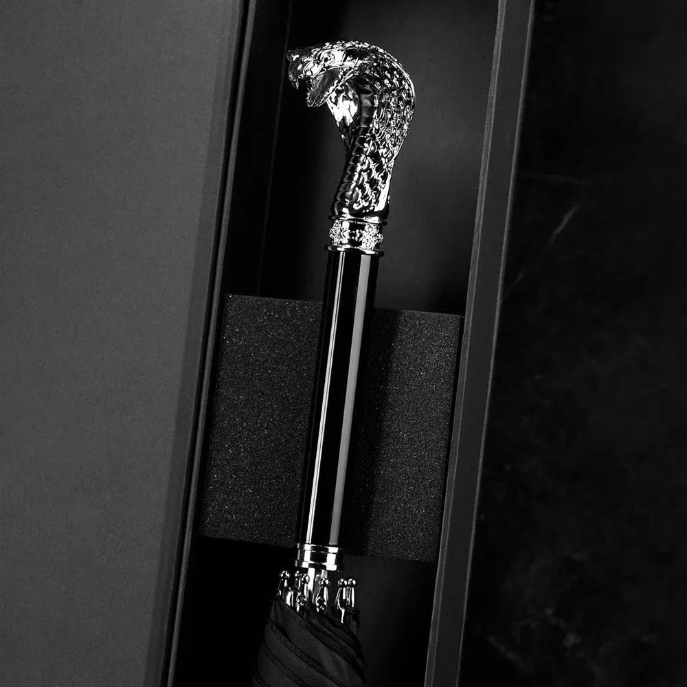 The detailed silver cobra head handle of the luxury parasol presented in its packaging.