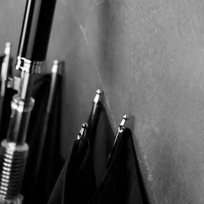 Monochrome detail shot of the metal tip on the edge of the closed black canopy of the lion head umbrella.