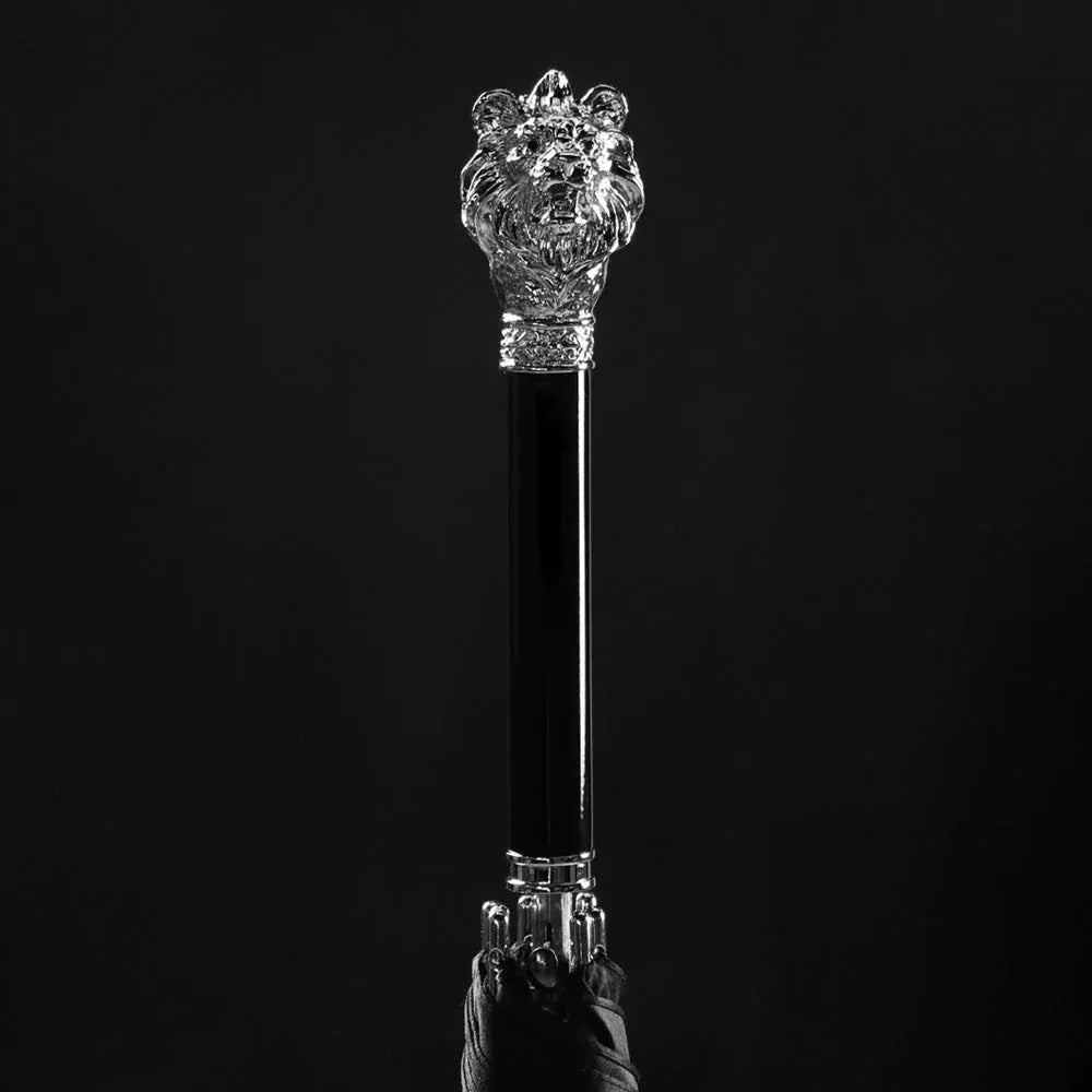 Dramatic close-up of the sculpted silver lion head handle against a pure black background.